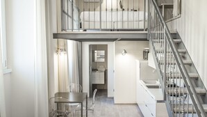 A modern apartment with a dining area, kitchen, and a loft bedroom with a balcony. - Brera Apartments in San Marco (Milan)