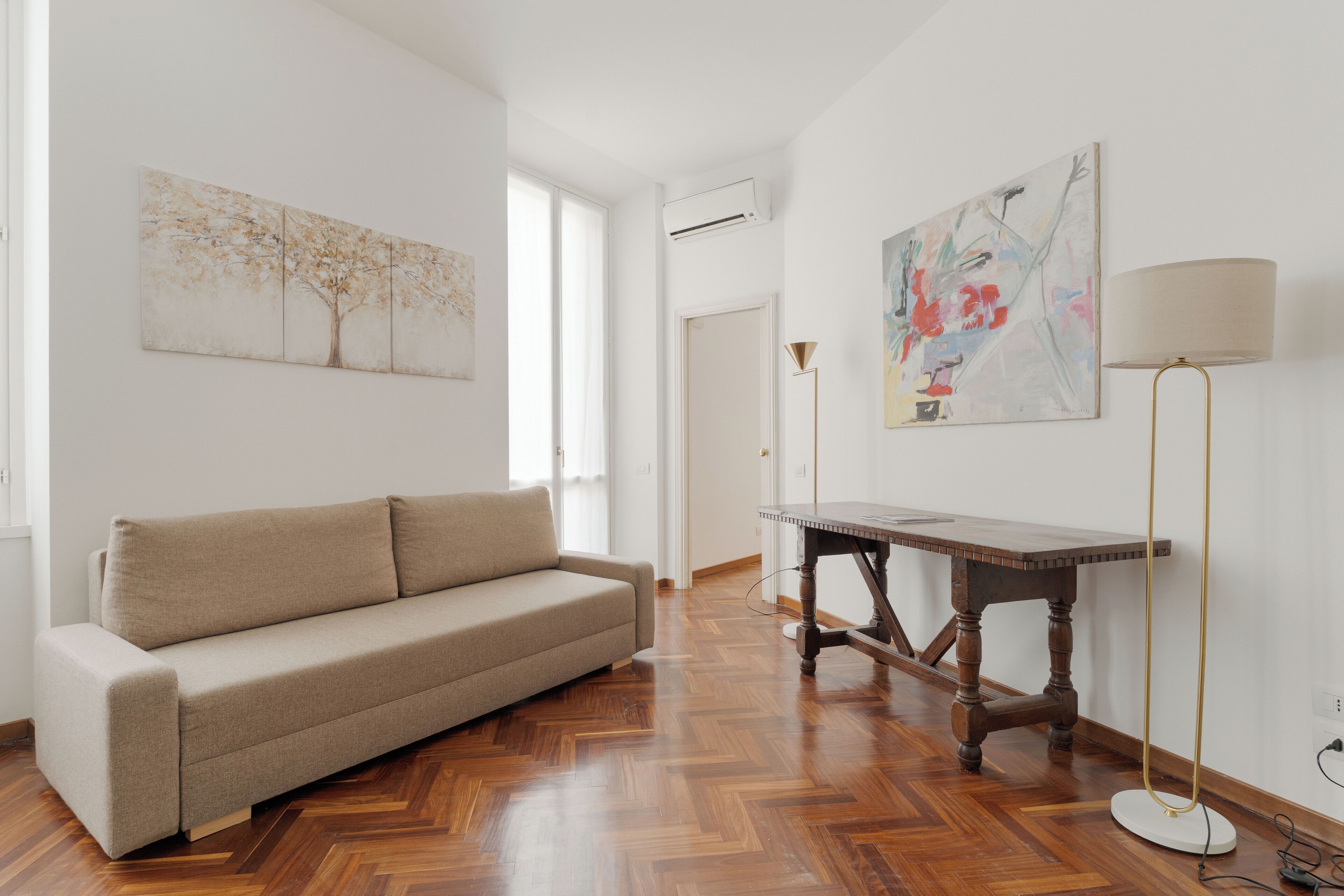 A living room with a sofa, a wooden table, and artwork on the walls.