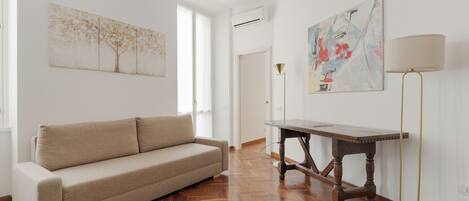 A living room with a sofa, a wooden table, and artwork on the walls.
