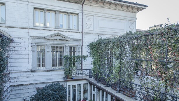 A white building with large windows and a balcony with iron railings. - Brera Apartments in San Marco (Milan)
