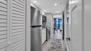 A modern kitchen with stainless steel appliances, a marble backsplash, and a view to the dining area.