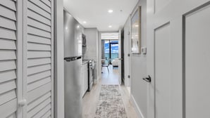 A hallway with a kitchen area, a dining area, and a view of the sky.
