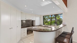 Una cocina moderna con armarios blancos, encimera de granito y horno empotrado.