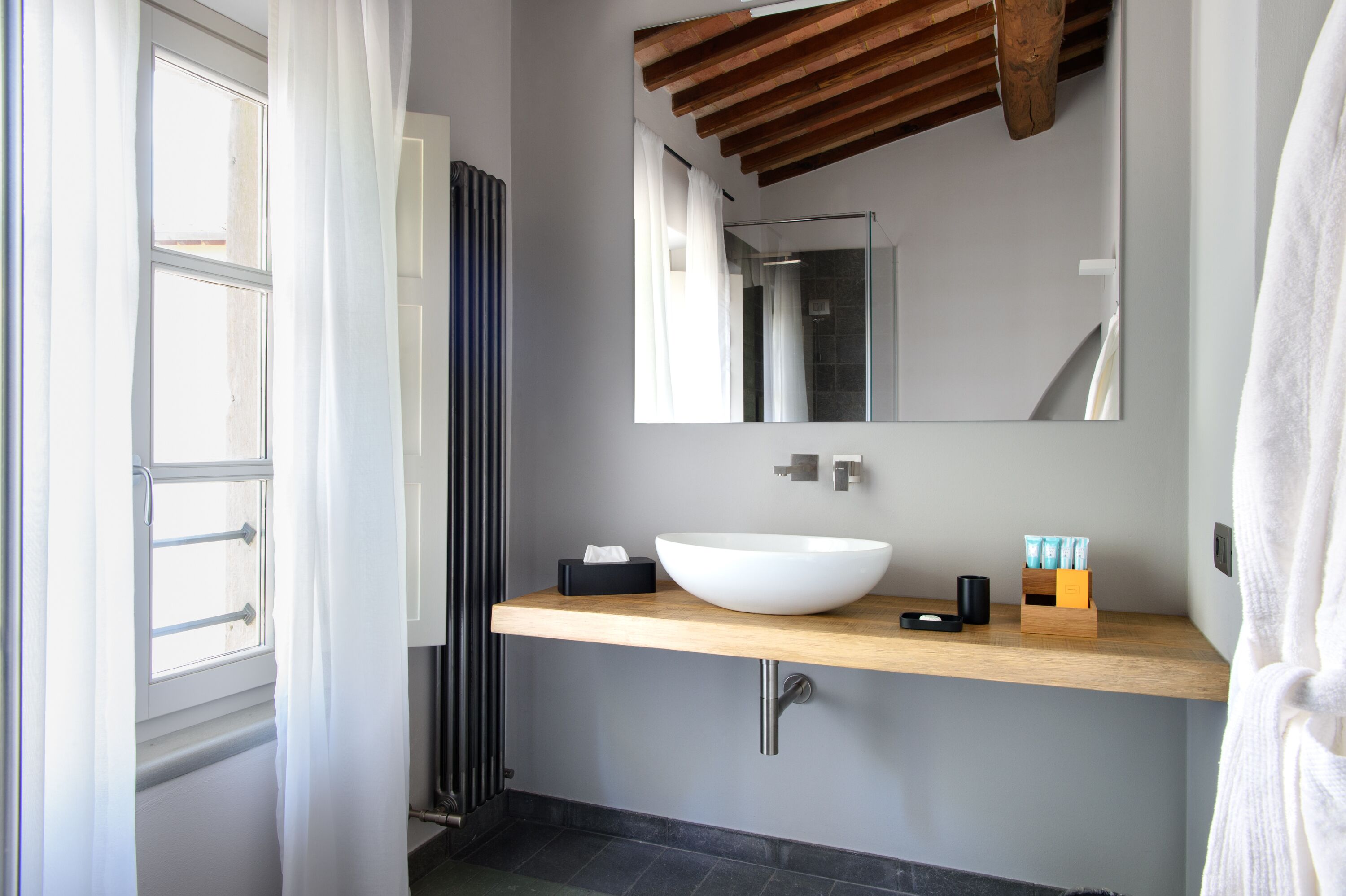 Une salle de bain moderne avec un grand miroir, un lavabo blanc et un plan de travail en bois.