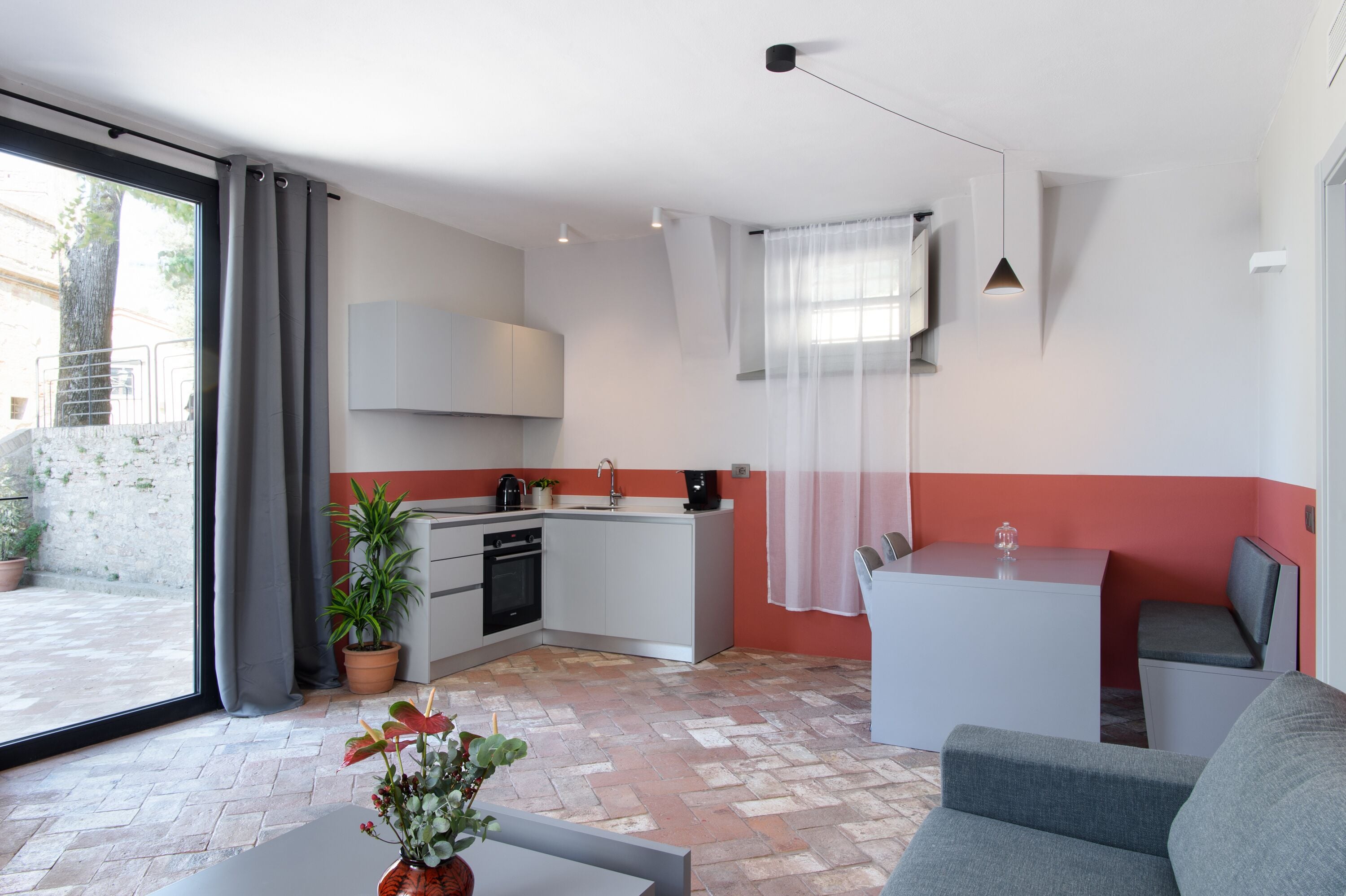 Una cocina compacta con comedor, una planta en maceta y vistas a través del ventanal.