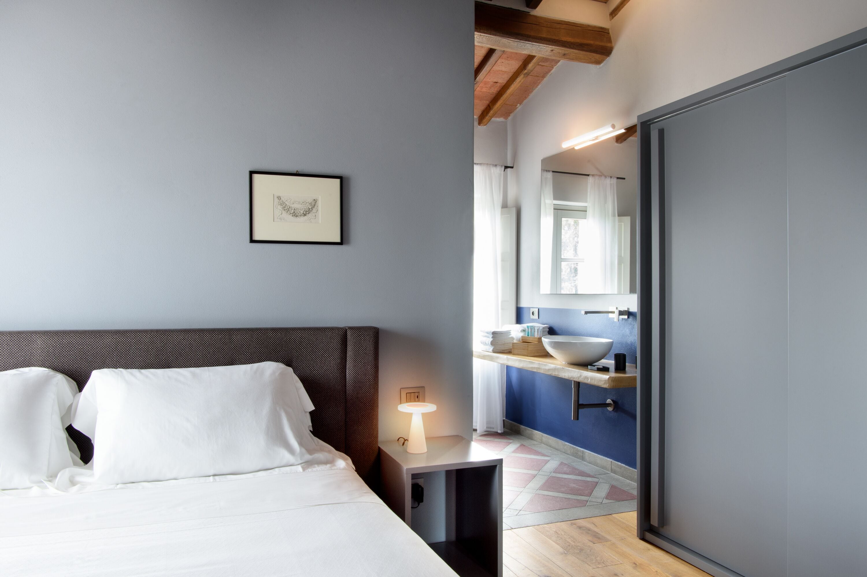 A modern bedroom with a bed, bedside table, and a framed picture on the wall.