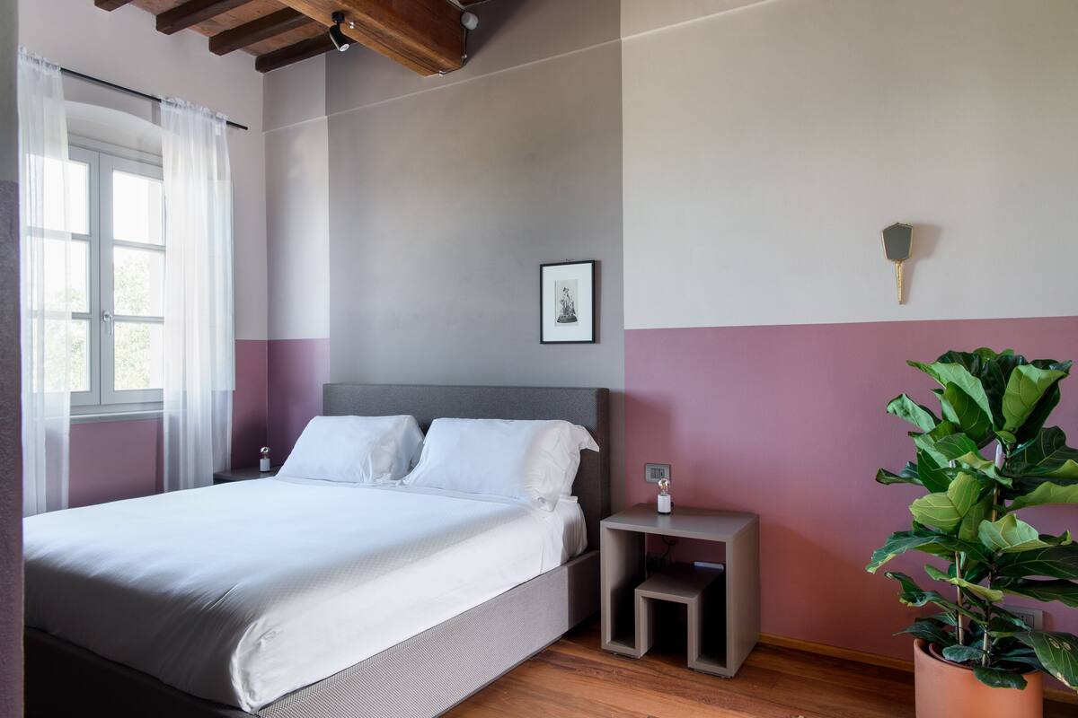 A neatly arranged bedroom with a bed, bedside table, and a potted plant.