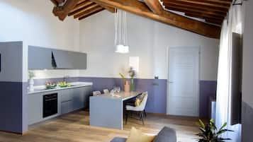 Una cocina moderna con una isla central, vigas de madera y un comedor con sofá y sillas.