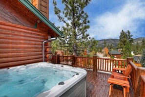 A hot tub on a wooden deck with a view of trees and mountains. - Sky Pine Retreat by Destination Big Bear: Log Cabin Home! Game Room! HOT TUB! EV Charger! (Big Bear Lake)