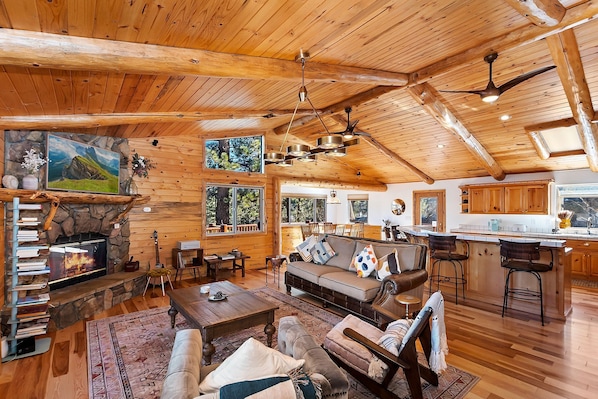 Un amplio salón con chimenea, techo de madera y una acogedora zona de estar.
