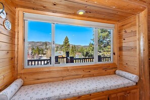 Una cabaña de madera con un ventanal grande que ofrece vistas a un paisaje montañoso.