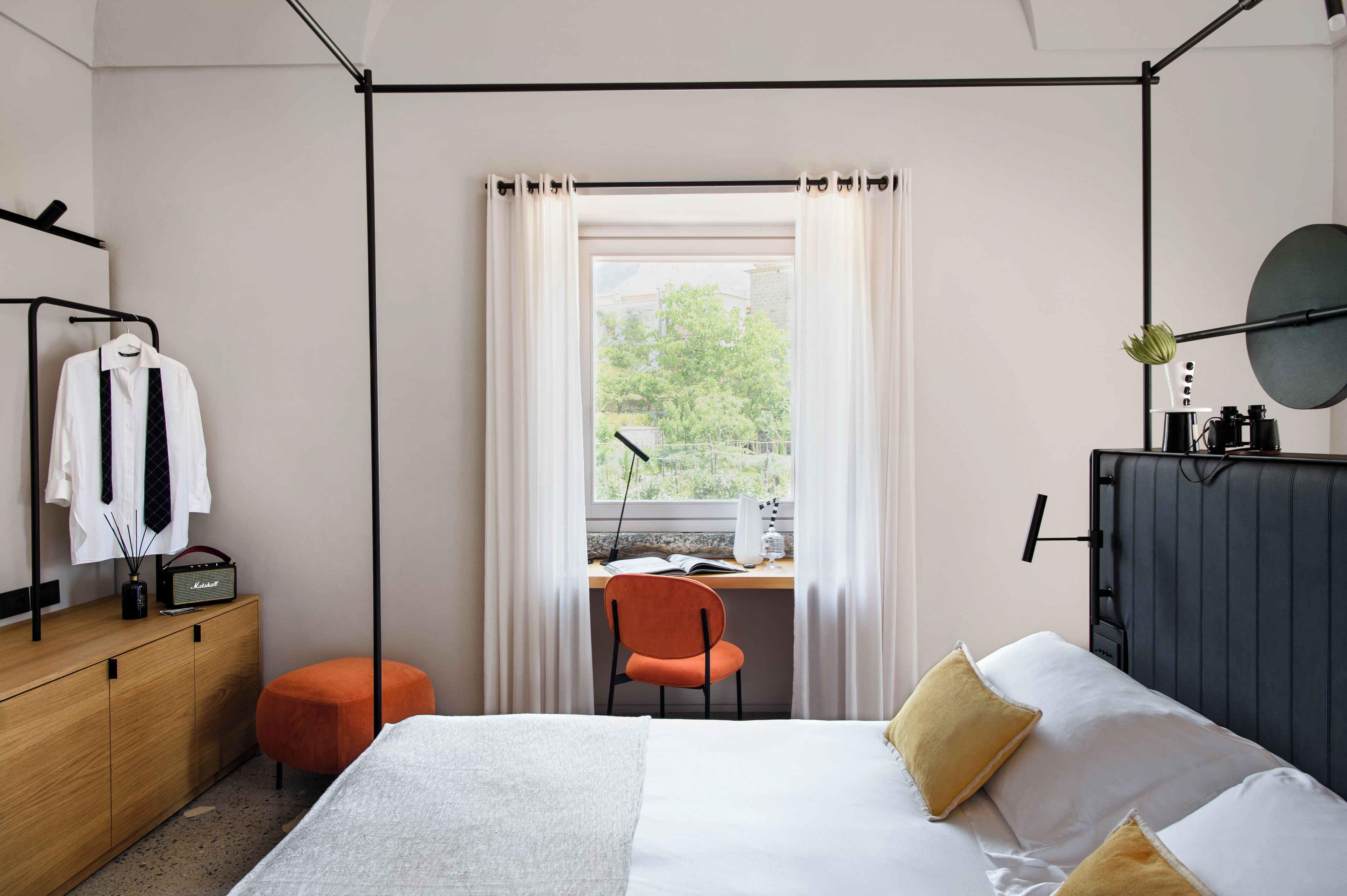 Ein Schlafzimmer mit einem Bett, einem Schreibtisch mit Stuhl, einem Kleiderschrank und einem Fenster mit Vorhängen.