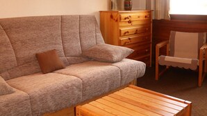 Een woonkamer met een bank, een houten bijzettafeltje, een houten dressoir en een stoel.