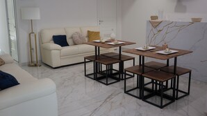 Un saló modern amb un sofà, una taula de centre i una taula de dinar amb quatre cadire.