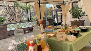 Zona de dinar exterior coberta amb una taula preparada per a les menjades, incloent diversos plats, begudes i un fanal decoratiu.