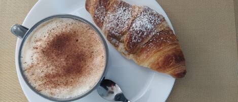 Un plato con un croissant y una taza de café.