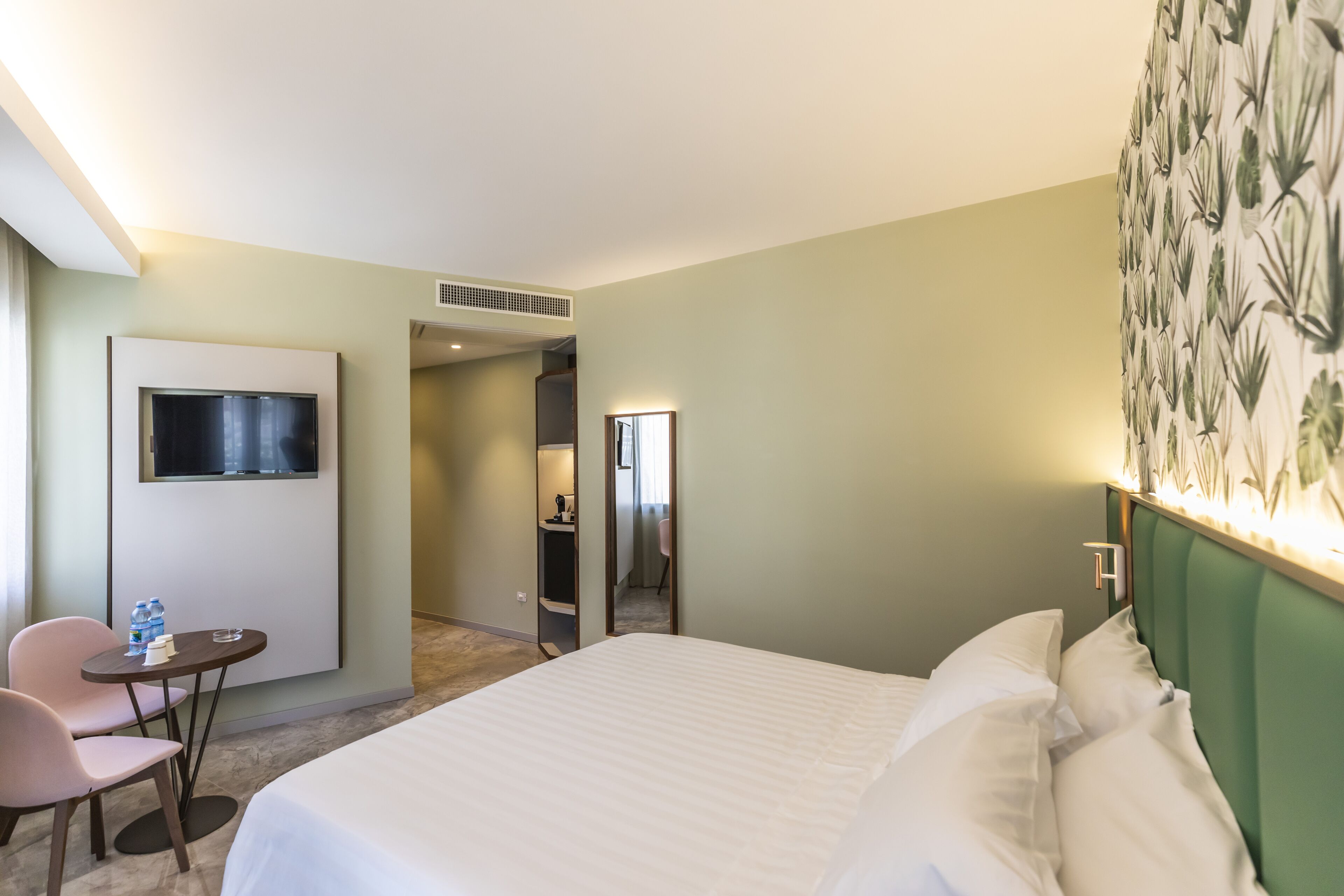 Une chambre d’hôtel avec un lit, un bureau et une chaise, une télévision et une salle de bain visible à travers une porte ouverte.