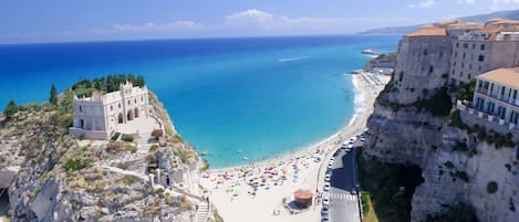 A coastal town with a historic building, a beach, and a cliffside road.