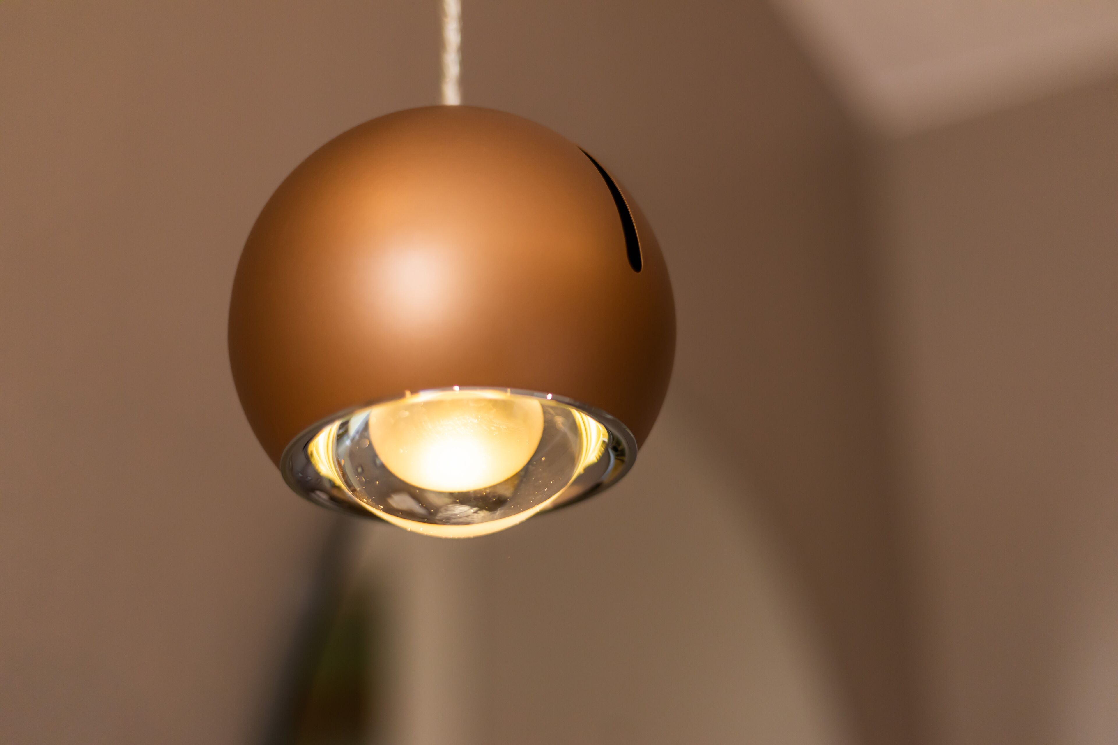 Luminária pendente esférica com lâmpada aparente.