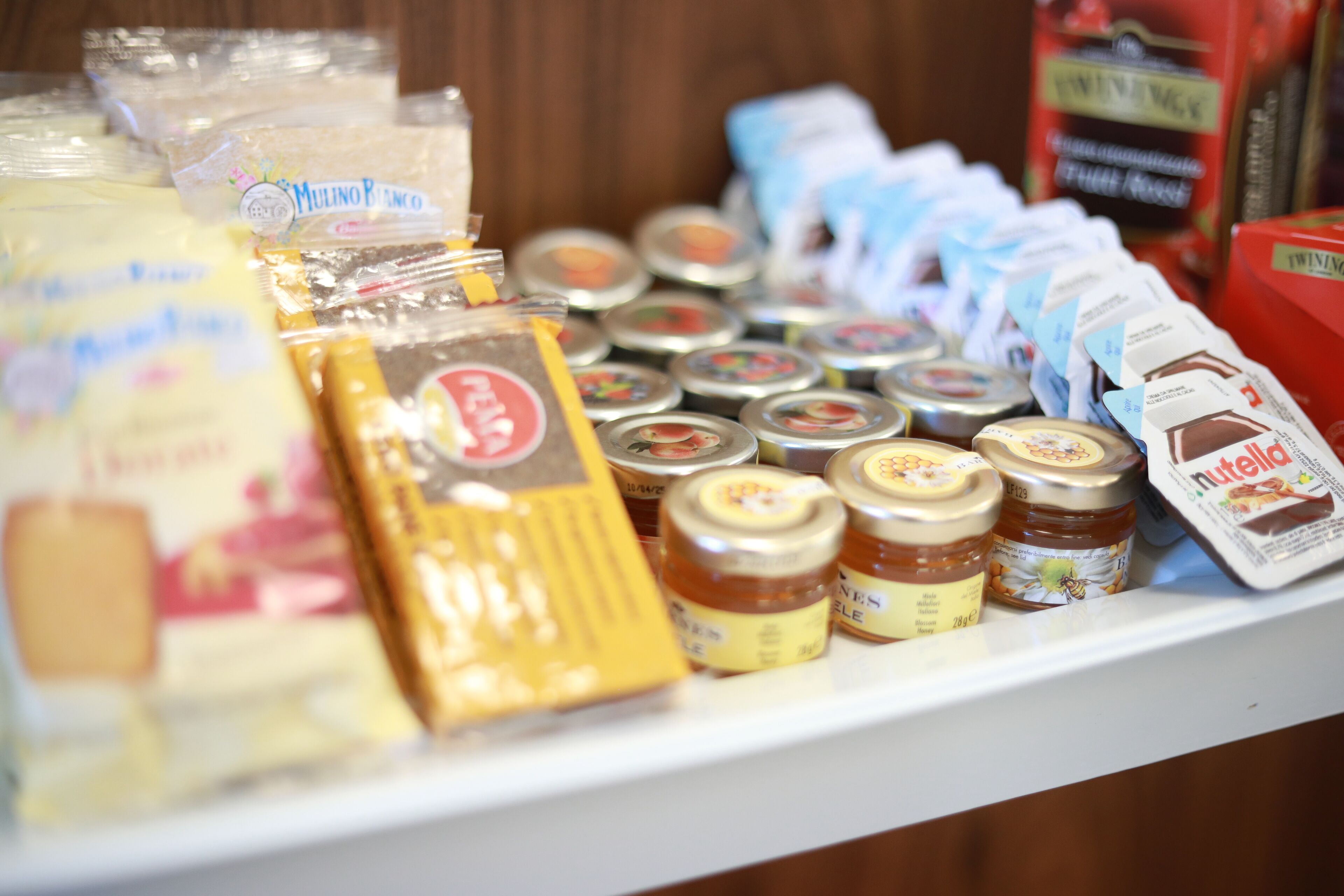 A variety of packaged food items on a shelf, including jars of honey and packets of butter.