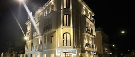 Un hotel de varios pisos con fachada moderna, balcones y una entrada bien iluminada.