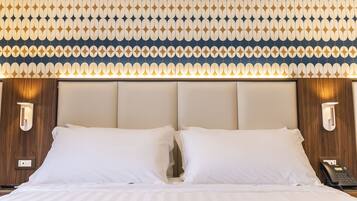 Une chambre d’hôtel avec un grand lit, deux lampes de chevet et un mur décoré d’un motif.