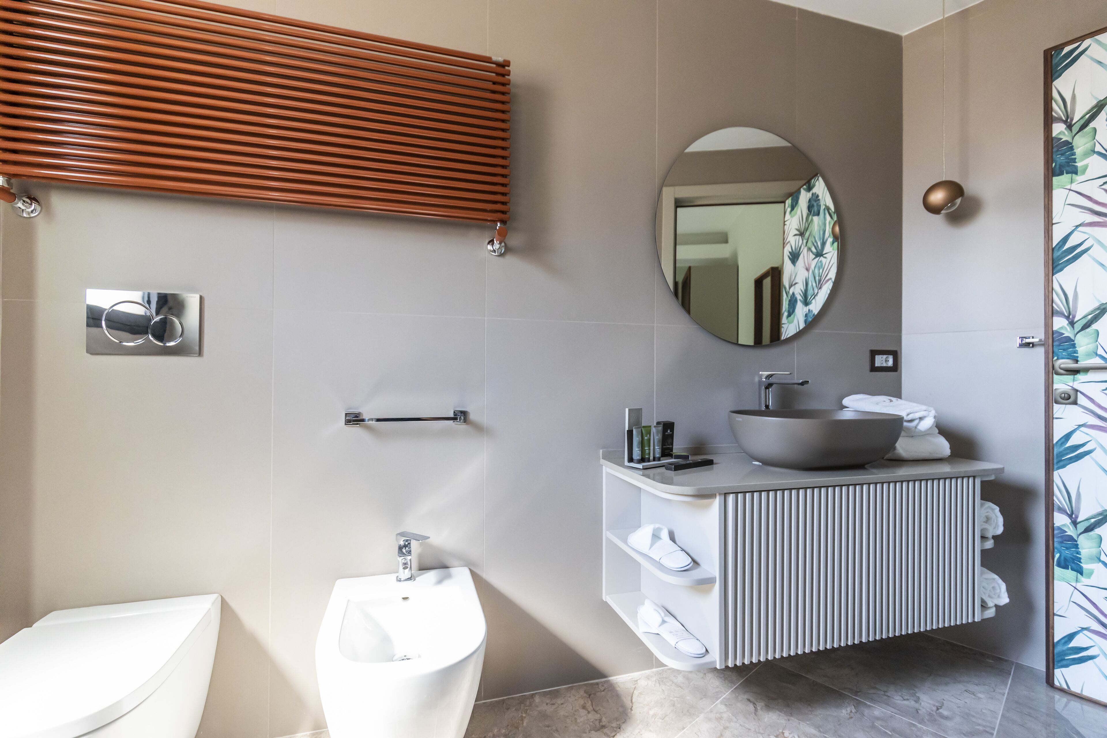 Een moderne badkamer met een bidet, een wastafel met een komgootsteen en een handdoekhouder.