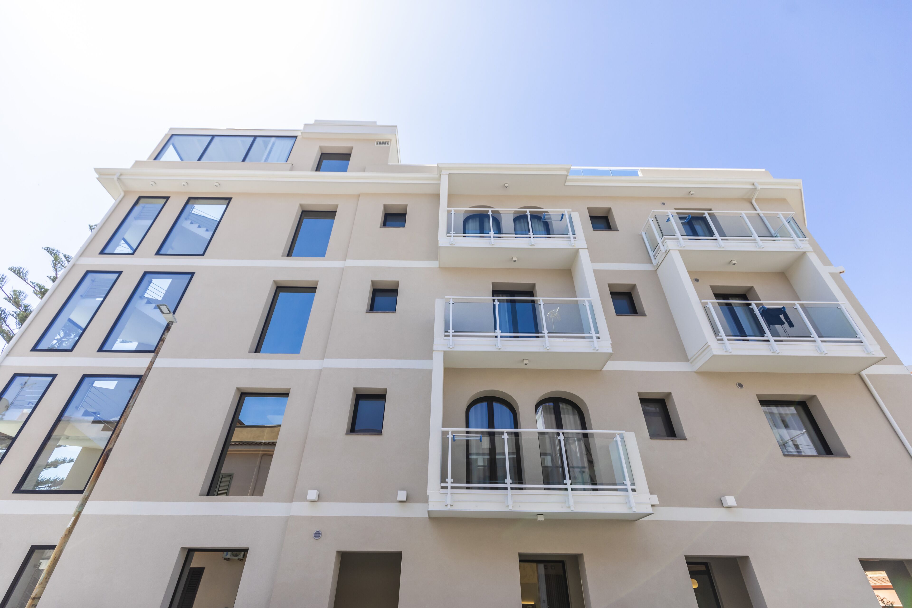 Un edificio de varios pisos con balcones, ventanas amplias y fachada plana.