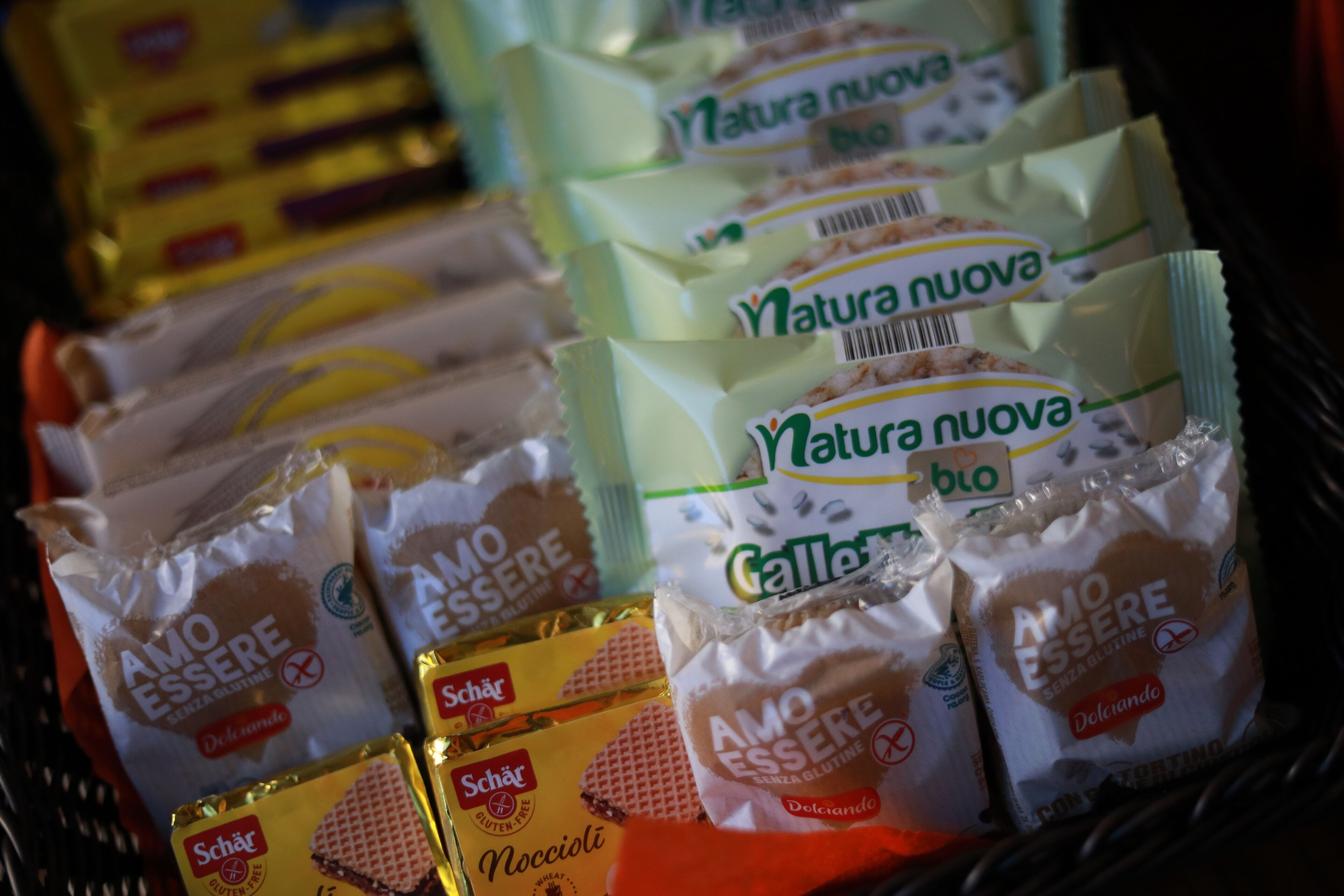 A variety of packaged food items, including 'Amo Eser' and 'Schär' brands, arranged on a shelf.