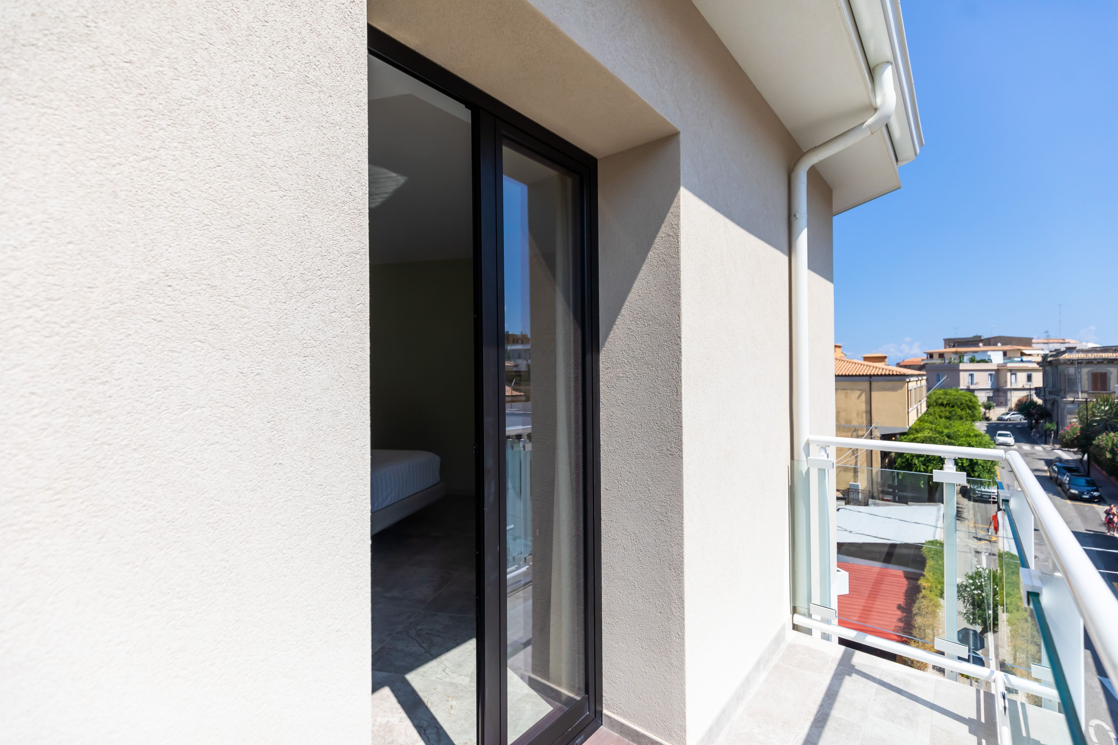 A balcony with a glass door leading to a bedroom.