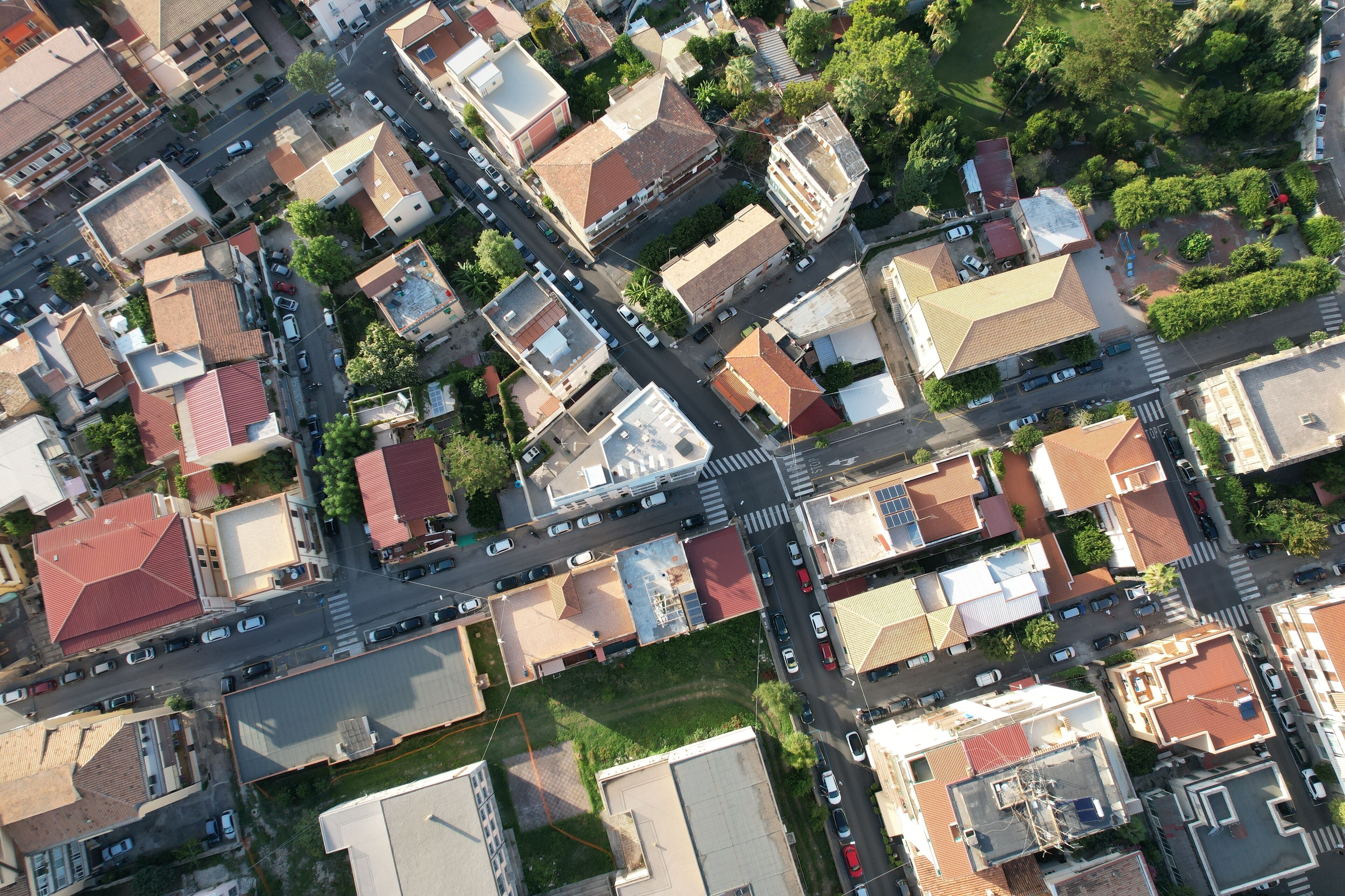 An aerial view of a residential area with multiple buildings, roads, and vehicles.