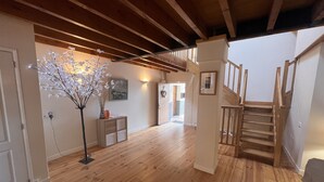 A spacious room with wooden floors, a staircase, and a decorative tree with lights. - Tranquil and spacious gîte with own pool near market town (Lezay)