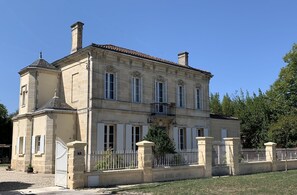 Um edifício grande e histórico com fachada simétrica, várias janelas e entrada com portão.