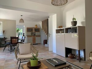 Ein geräumiger Wohnbereich mit einer Couch, einem Esstisch und einer Küche im Hintergrund.