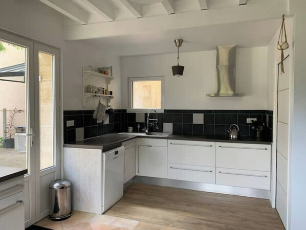 Una cocina moderna con armarios blancos, un salpicadero de azulejos negros y piso de madera.