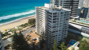 A high-rise hotel with multiple balconies, a pool, and a beach view.