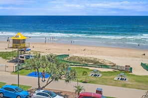 A beach with a lifeguard tower, a sandy shore, and a clear blue sky.