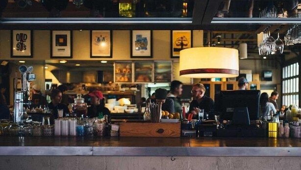 A bar area with a counter, various bottles, and framed pictures on the wall.