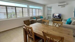 A spacious living room with a dining table, chairs, a sofa, and a television.