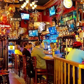 Un bar con varias televisiones, una variedad de botellas y un cartel que dice 'Ocean Pky'.