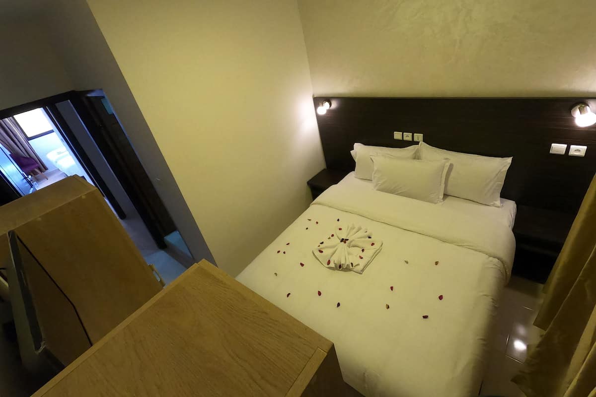 A hotel room with a bed, bedside tables, and a view of the hallway.