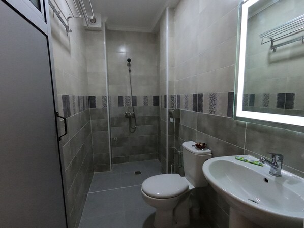 A compact bathroom with a toilet, sink, and shower. - Hotel Marina Dreams Dakhla (Dakhla)