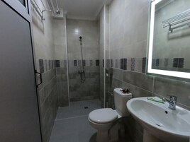 Un baño pequeño con inodoro, lavamanos y ducha.