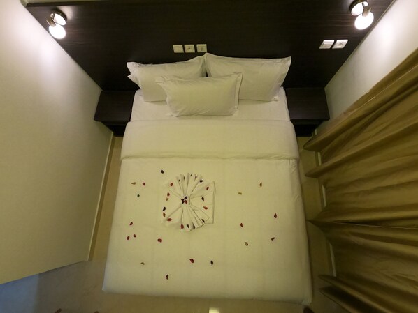 A neatly made bed with white linens and a decorative fan arrangement, a dark wooden headboard, and a staircase with beige curtains. - Hotel Marina Dreams Dakhla (Dakhla)