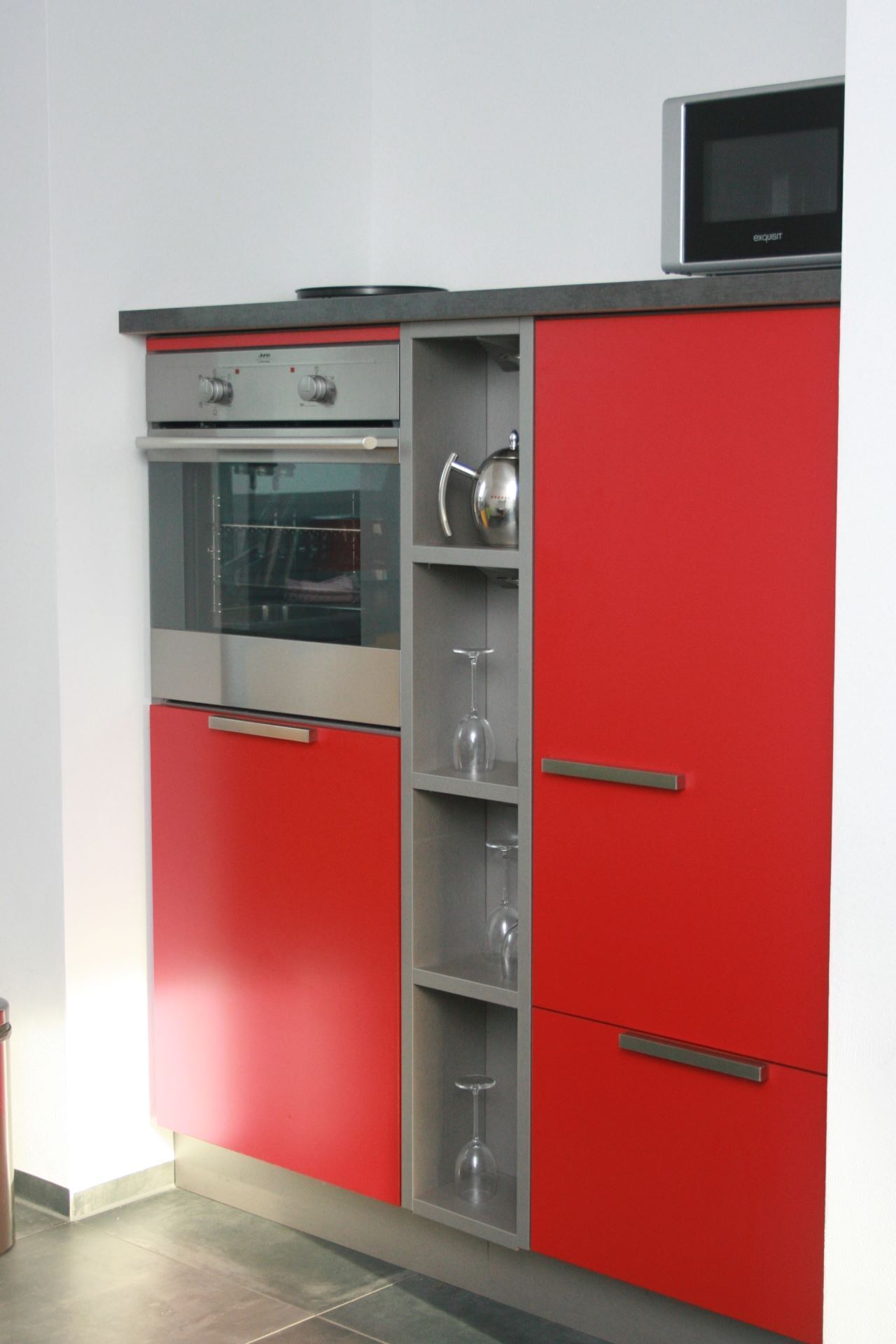 Cozinha com armários vermelhos, forno de aço inoxidável e micro-ondas.