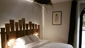 Een slaapkamer met een bed, een houten hoofdbord, bedlampen en een lijst met een afbeelding aan de muur.
