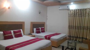 A hotel room with two beds, each with red and white bedding, a small table, and an air conditioning unit on the wall. - Hotel Pak Inn Gulberg (Lahore)