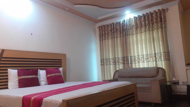 A hotel room with a bed, a chair, and curtains. - Hotel Pak Inn Gulberg (Lahore)