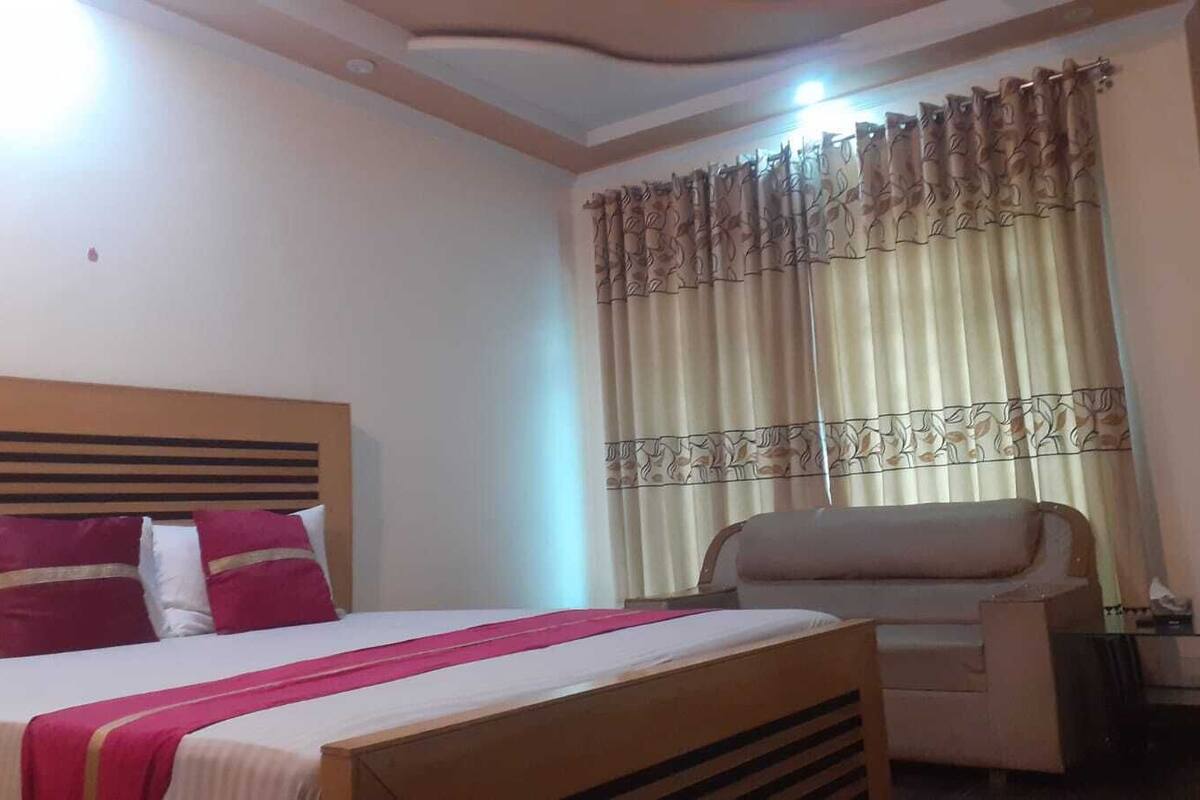 Une chambre d’hôtel avec un lit, une chaise et des rideaux.