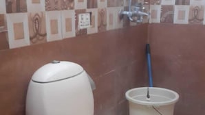 A bathroom with a toilet, a bucket, and a showerhead. - Hotel Pak Inn Gulberg (Lahore)